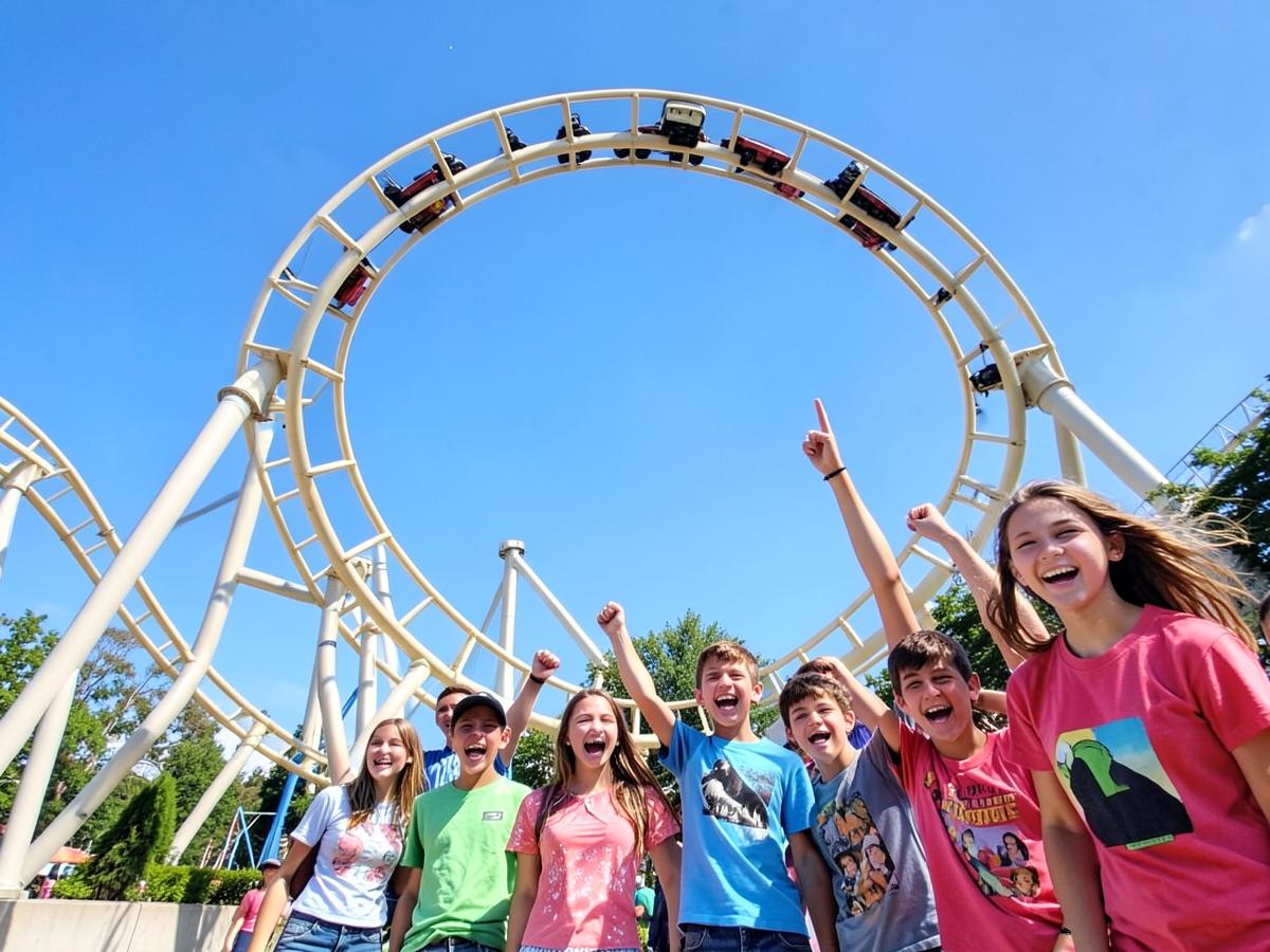 Montanha-russa com looping e jovens comemorando em dia de sol